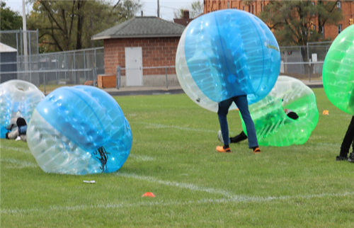 3 students inside of blue and green inflatable ball